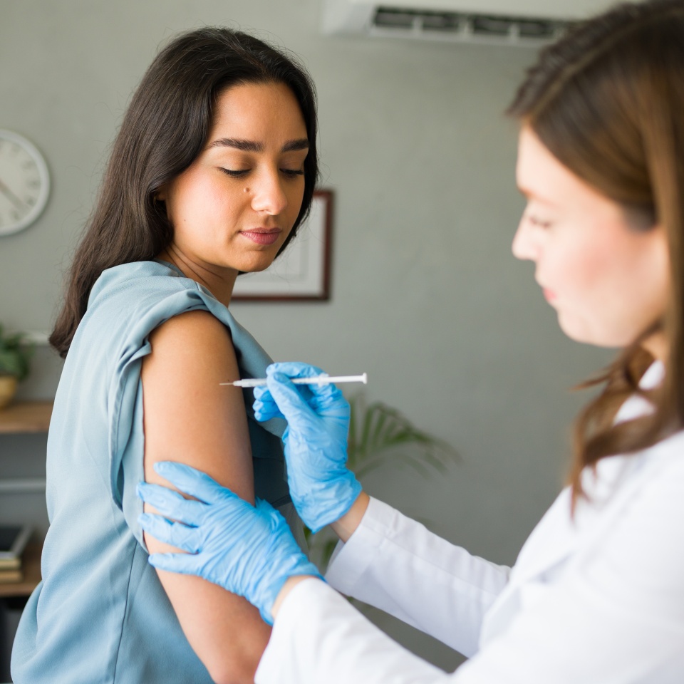 Young woman is receiving a vaccine shot from a medical professional, promoting health and well-being