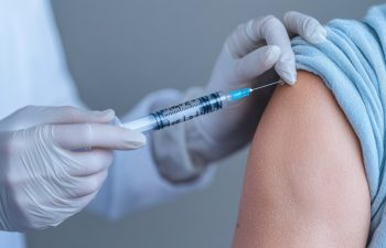 A healthcare professional administering a vaccine to a patient's arm, highlighting the importance of vaccinations for health.