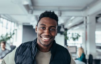 Smiling designer standing in workplace and looking at camera. Handsome young man in design office.