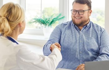 Doctor and patient consultation ends with handshake. A friendly clinician gives advice on weight loss, nutrition and healthier habits. Successful healthcare partnership and motivation.