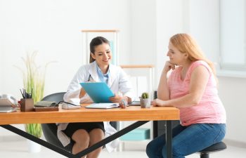 Young female doctor consulting overweight woman in clinic
