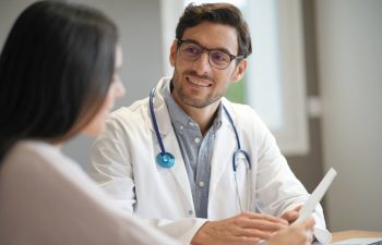Modern young doctor speaking to patient in office