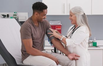 A doctor checks a patient's blood pressure in a medical examination room.