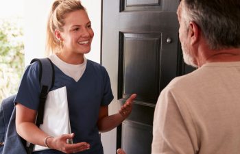 Senior man opening his front door to a female healthcare worker making a home health visit
