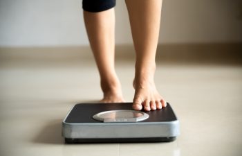 Female leg stepping on weigh scales. Healthy lifestyle, food and sport concept.