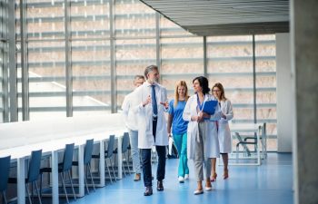 Group of doctors walking in corridor on medical conference, talking.