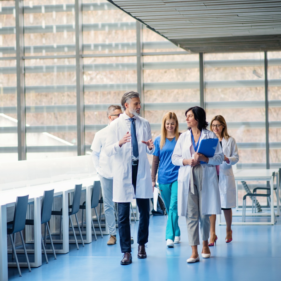 Group of doctors walking in corridor on medical conference, talking.