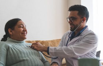 Young Latin American Doctor Checking Patient at Home. Doctor Checking Heartbeat of Patient . Doctor Doing Home Service. Healthcare Concept.