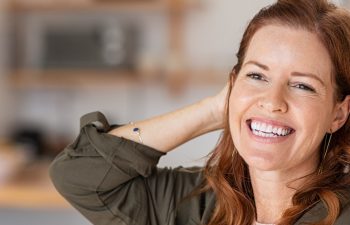 Portrait of beautiful mature woman at home. Successful middle aged woman smiling and looking away while touching hair. Mid redhead lady laughing and relaxing.