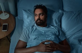 sleeping, insomnia and people concept - speelpess indian man lying in bed at home at night