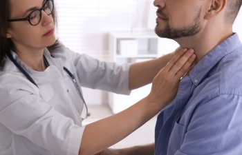 Doctor examining thyroid gland of patient in hospital, closeup