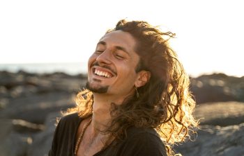 Portrait of happy handsome hippie italian man with long hair smiling beautiful . Freedom. Wanderlust. Tropics. Traveler.Beach. Relax. Tourism.