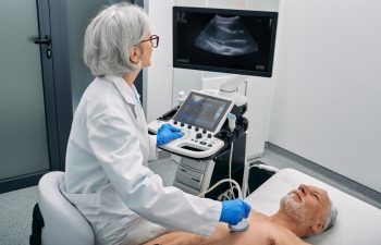 Heart ultrasound exam for senior man with ultrasound specialist while medical exam at hospital