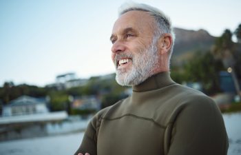 Surf, happy and senior man at the beach for peace, calm or freedom of the mind during holiday in Rio de Janeiro Brazil. Wetsuit, retirement sports and elderly person relax before surfing for wellness.