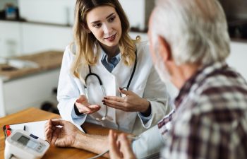 Female doctor measuring blood pressure of a senior man during a home visit