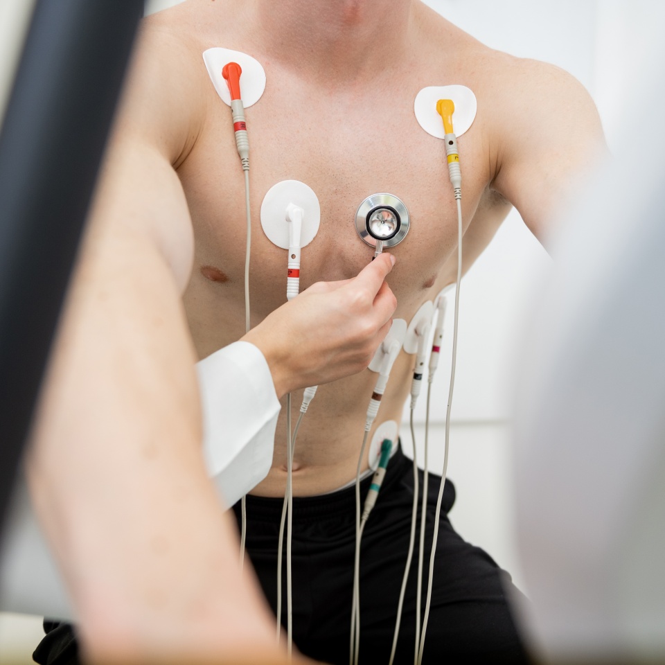 A focused individual performs a stress test on a treadmill, connected to monitoring equipment.