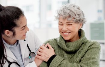Happy, care and face of a doctor with a woman for medical trust, healthcare and help. Laughing, hug and portrait of a young nurse with a senior patient and love during a consultation at a clinic.