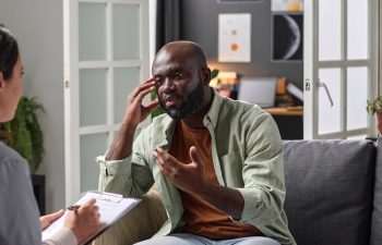 Portrait of adult African American man talking to psychotherapist in one on one session copy space