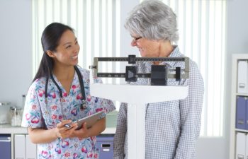 Chinese nurse weighing elderly patient