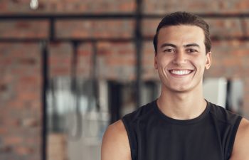 Man, portrait and confident in gym for fitness or daily workout routine, muscle growth and development. Male person, arms crossed and happy with pride in studio for exercise, cardio and training