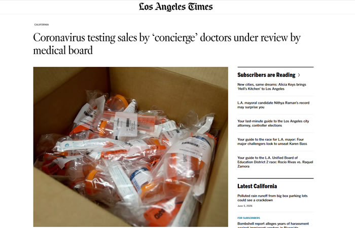 A cardboard box filled with individually packaged coronavirus test kits sits on a table.