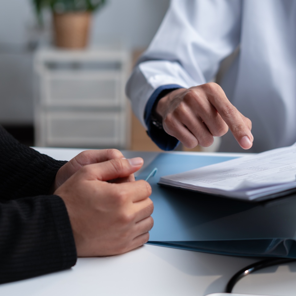 Doctor reviewing medical records with a patient during consultation, explaining healthcare documents, diagnosis, treatment options, clinical results, insurance and personalized care planning.