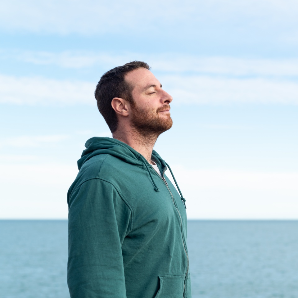 Relaxed man breathing fresh air with the sea at the background.