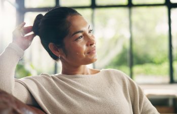 Couch, thinking and woman in home with smile for inspiration, break or resting in lounge. Daydreaming, calm and mature person in living room for reflection, relax and contemplating on sofa in house.